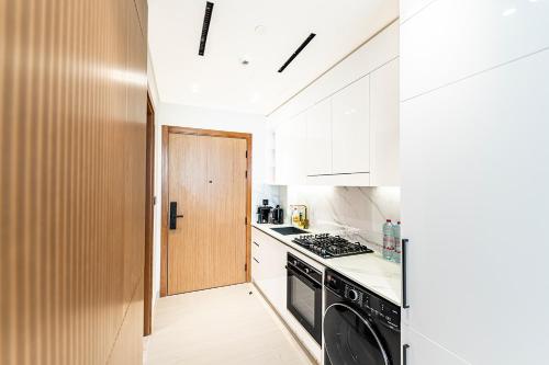 a kitchen with white cabinets and a black dishwasher at 15 min from Dubai Marina & JBR beach Studio apartment AZURE BINGHATTI JVC in Dubai