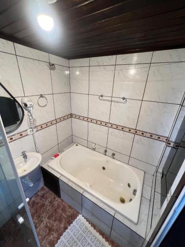 a bathroom with a bath tub and a sink at Pousada Coração da Ilha do Mel in Ilha do Mel