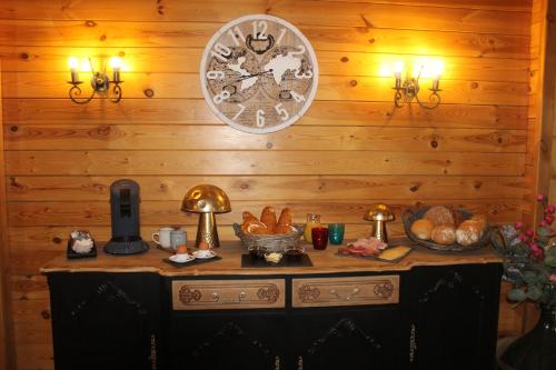 a clock on a wooden wall with a table with bread at A la campagne in Gouvy