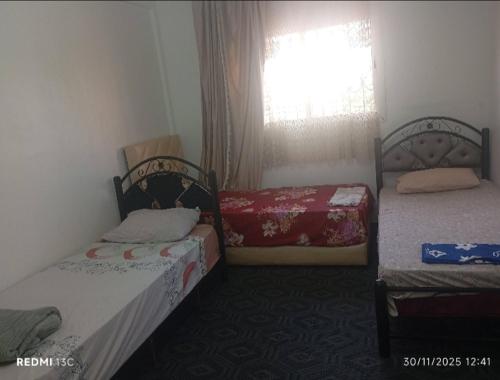 two beds in a small room with a window at Family House in Agadir