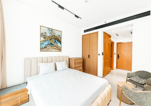 a bedroom with a white bed and a chair at 15 min from Dubai Marina & JBR beach Studio apartment AZURE BINGHATTI JVC in Dubai