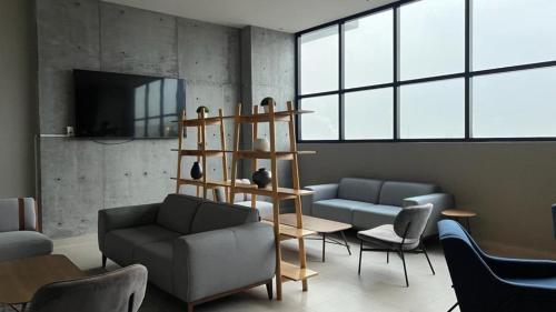 a living room with a couch and chairs and a table at Estilo Minimalista frente Arena y Parque Fundidora in Monterrey