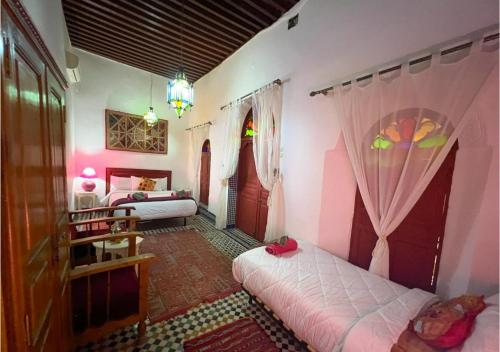 a bedroom with two beds with pink walls at Riad Iman in Fès