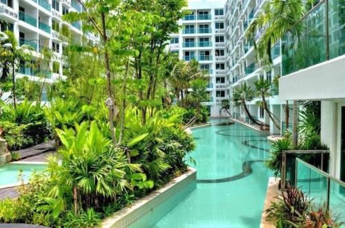 a swimming pool in a building with trees and plants at Amazon Condo, Building B, ground floor with direct pool access in Jomtien Beach