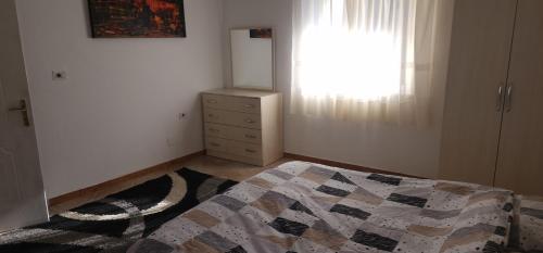 een slaapkamer met een bed, een ladekast en een raam bij Villa Star in Tirana