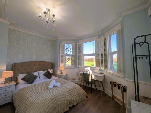 a bedroom with a bed and a desk and windows at Lakeside Oxford Hotel in Oxford