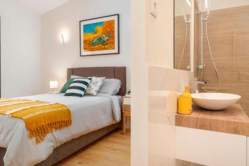 Un dormitorio con una cama y un baño con lavabo. en Casa De Mariposas Viola, en Faro