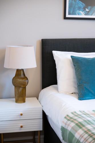 a bed with a night stand with a lamp on it at Shenley House- Premium Stay, Private Parking for multiple cars, Sleeps 6, 2 Bedroom, 2 Ensuites, Central MK in Milton Keynes