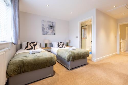 a bedroom with two beds and a window at Shenley House- Premium Stay, Private Parking for multiple cars, Sleeps 6, 2 Bedroom, 2 Ensuites, Central MK in Milton Keynes