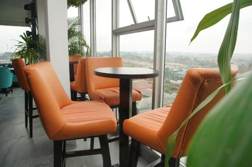 Hotel Exotic Plaza في دوالا: مجموعة من الكراسي البرتقالية وطاولة في غرفة