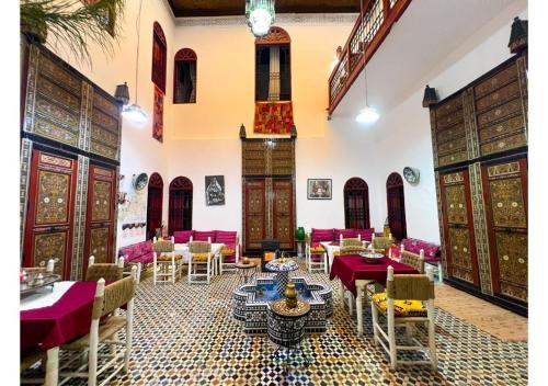 a restaurant with tables and chairs in a room at Riad Iman in Fès