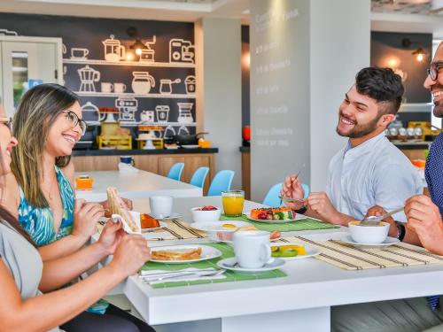 a group of people sitting around a table eating food at ibis Styles Vitoria da Conquista in Vitória da Conquista