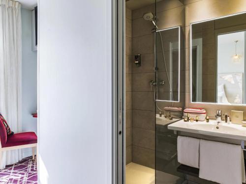 un baño con lavabo y espejo en Mercure Paris Pont de Levallois Neuilly, en Levallois-Perret