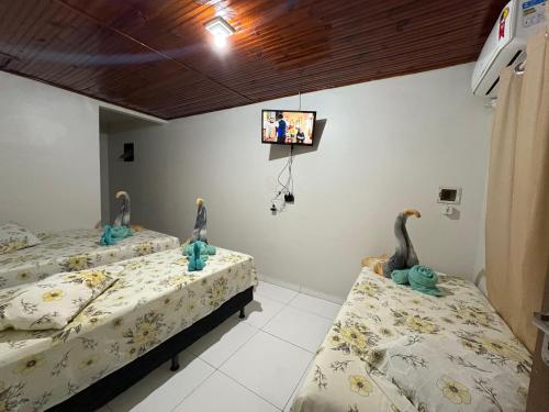 due letti in una stanza con una TV a parete di Residencial Filhos da Lua a Lençóis