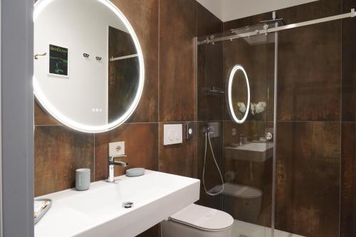 ein Badezimmer mit Waschbecken, Spiegel und Dusche in der Unterkunft Rooms Around in Neapel