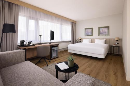 a hotel room with a white bed and a desk at NH Atlanta Rotterdam Hotel in Rotterdam