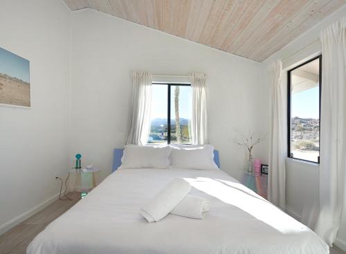 een witte slaapkamer met een groot wit bed en een raam bij The Giddyup in Pioneertown