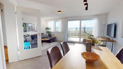 a dining room and living room with a table and chairs at HEIMATEL - Ferienhaus im Alpenblick in Primisweiler