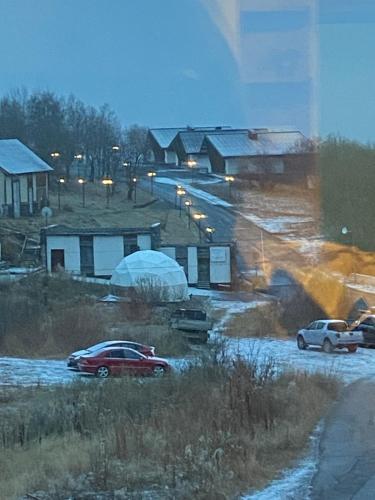 Un coche rojo aparcado en la nieve delante de las casas. en axis, en Kʼumlistsʼikhe