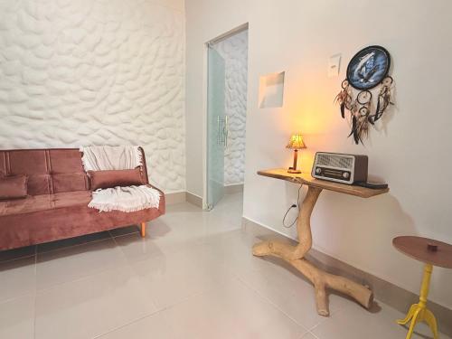 een woonkamer met een bank en een klok op een tafel bij Chalé Pequi, Romântico e espaçoso, com ar cond conforto e aconchego in Cavalcante