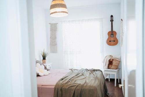a bedroom with a bed and a guitar in it at Casa Oceanchild - Terraza con Vista Mar, Morro Jable in Morro del Jable