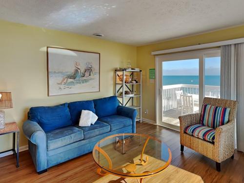 a living room with a blue couch and a glass table at Ocean Dunes 306 in Kure Beach