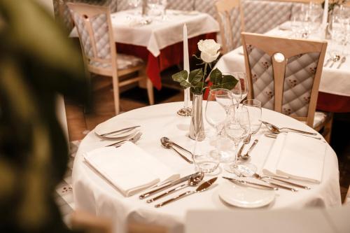 uma mesa com uma toalha de mesa branca e uma flor branca em Apartment Hotel Elvis em Ortisei