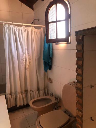ein Badezimmer mit Toilette und Fenster in der Unterkunft Hogar de luz in Olavarría