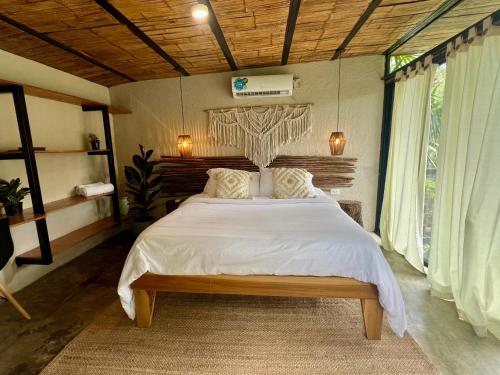 a bedroom with a large bed with white sheets at Costeño River Minca in Minca