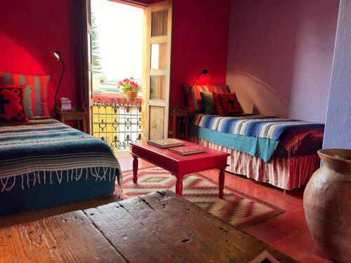 a room with two beds and a table and a window at Posada de la cruz#1 in Querétaro