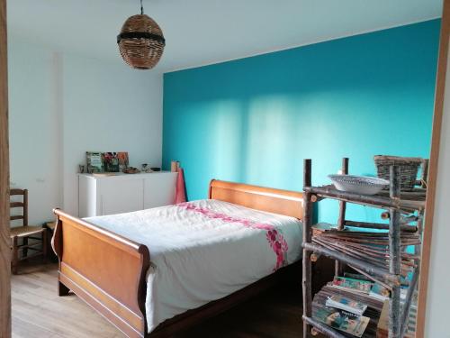 a bedroom with a bed and a blue wall at Chaleur des bois du Quercy in Montcuq