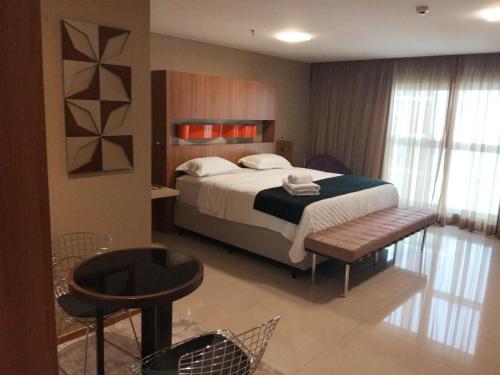 ein Schlafzimmer mit einem Bett, einem Tisch und Stühlen in der Unterkunft Flat Sofisticado no Jade Hotel Home Office in Brasilia