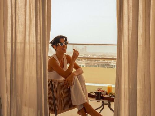 a woman in sunglasses sitting in front of a mirror at Grand Plaza Mövenpick Media City in Dubai