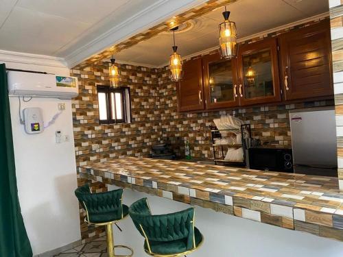 una cucina con un bancone con due sedie verdi di I&J Resort VIP a Yaoundé