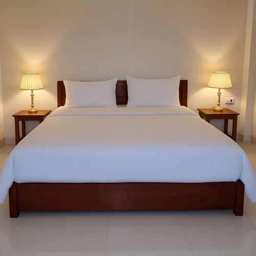 a large white bed with two lamps on two tables at Sipanya Guesthouse in Muang Phônsavan