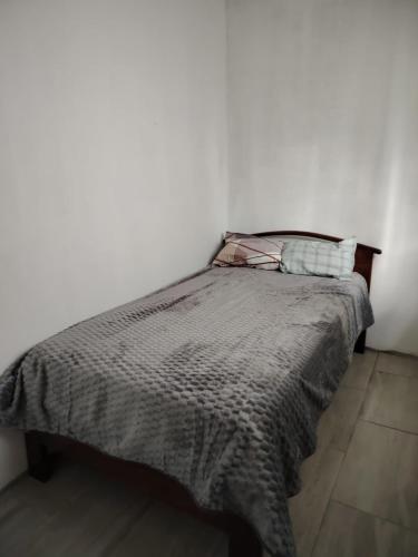 a bed in a room with a white wall at Coney Camping in Ambato