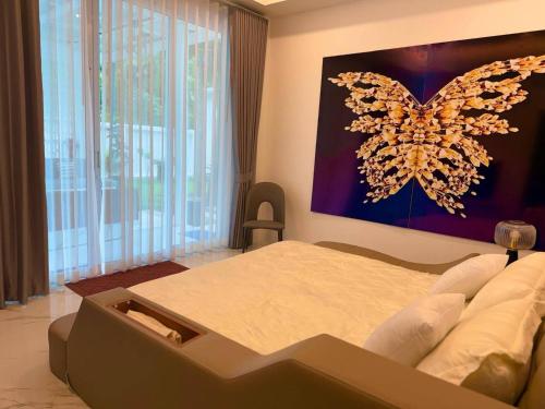 a bedroom with a large bed with a butterfly painting on the wall at Beautiful villa between jungle in Ban Chong Phli