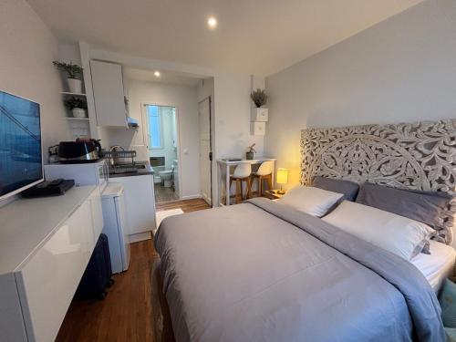 a bedroom with a large bed and a kitchen at Charmant studio - Vanves in Vanves