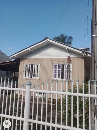 una pequeña casa con una valla blanca en Casa próximo ao Aeroporto, en Florianópolis