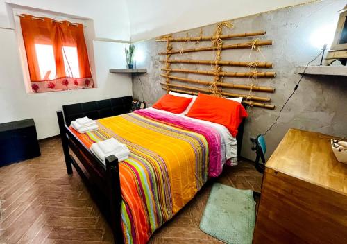 een slaapkamer met een bed met kleurrijke dekens en kussens bij Gli occhi del vulcano in Linera