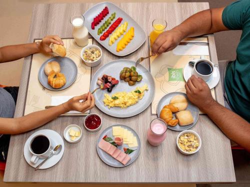 two people sitting at a table with breakfast food at ibis Styles Lima Benavides Miraflores in Lima