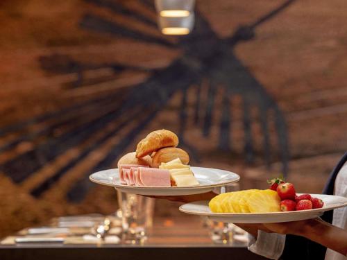 a person holding two plates of food on a table at ibis Styles Lima Benavides Miraflores in Lima