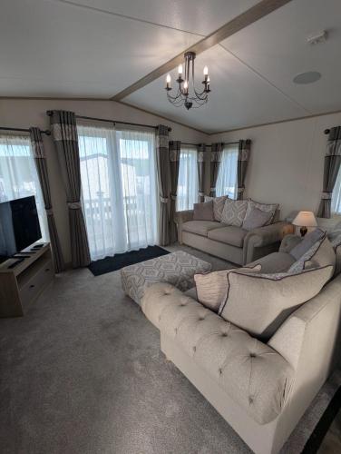 a living room with two couches and a tv at ABI Beaumont Luxury Caravan, Steps from Durdle Door in West Lulworth
