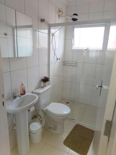 a bathroom with a toilet and a sink and a shower at Apartamento superior Boracéia in Bertioga
