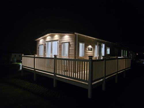 a small wooden house with lights on it at night at ABI Beaumont Luxury Caravan, Steps from Durdle Door in West Lulworth