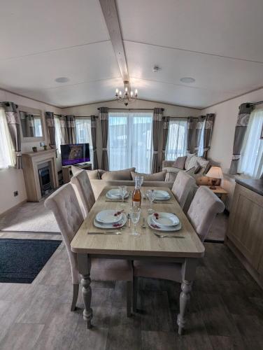 a dining room and living room with a table and chairs at ABI Beaumont Luxury Caravan, Steps from Durdle Door in West Lulworth