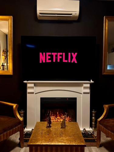 a living room with a fireplace with a tv above it at Winter CBD retreat,Fireplace,Free secure parking, Balcony, NETFLIX, FREE WIFI, Walk to Rundle St, UniAdelaide, Casino, Pubs, Cafes in Adelaide
