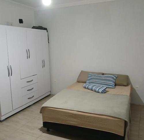 a bedroom with a bed and a white cabinet at Quartos em Arraial do Cabo in Arraial do Cabo