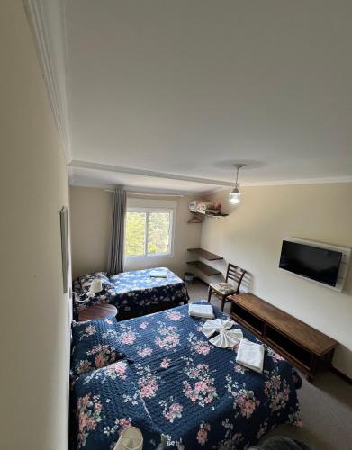 a hotel room with two beds and a tv at Pousada La Sierra in Campos do Jordão