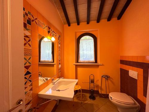 een oranje badkamer met een wastafel en een toilet bij Villa Mario & Friends in Pozzo